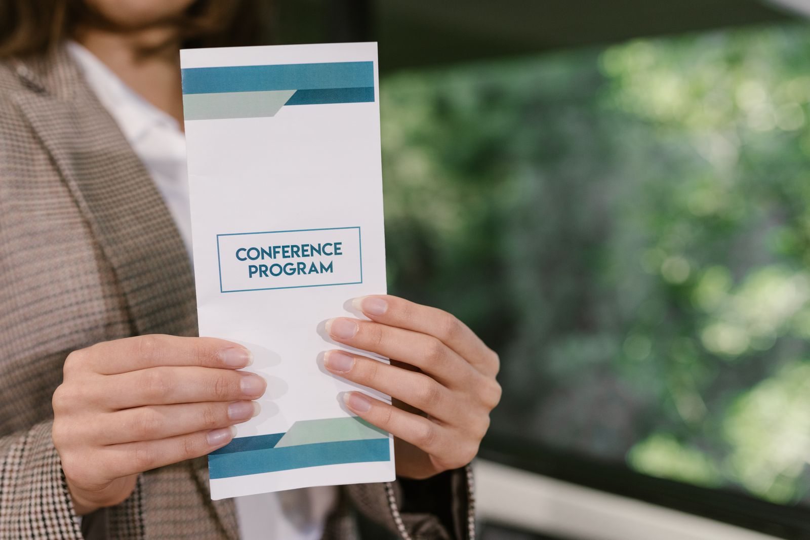 Person hält ein gedrucktes Konferenzprogramm