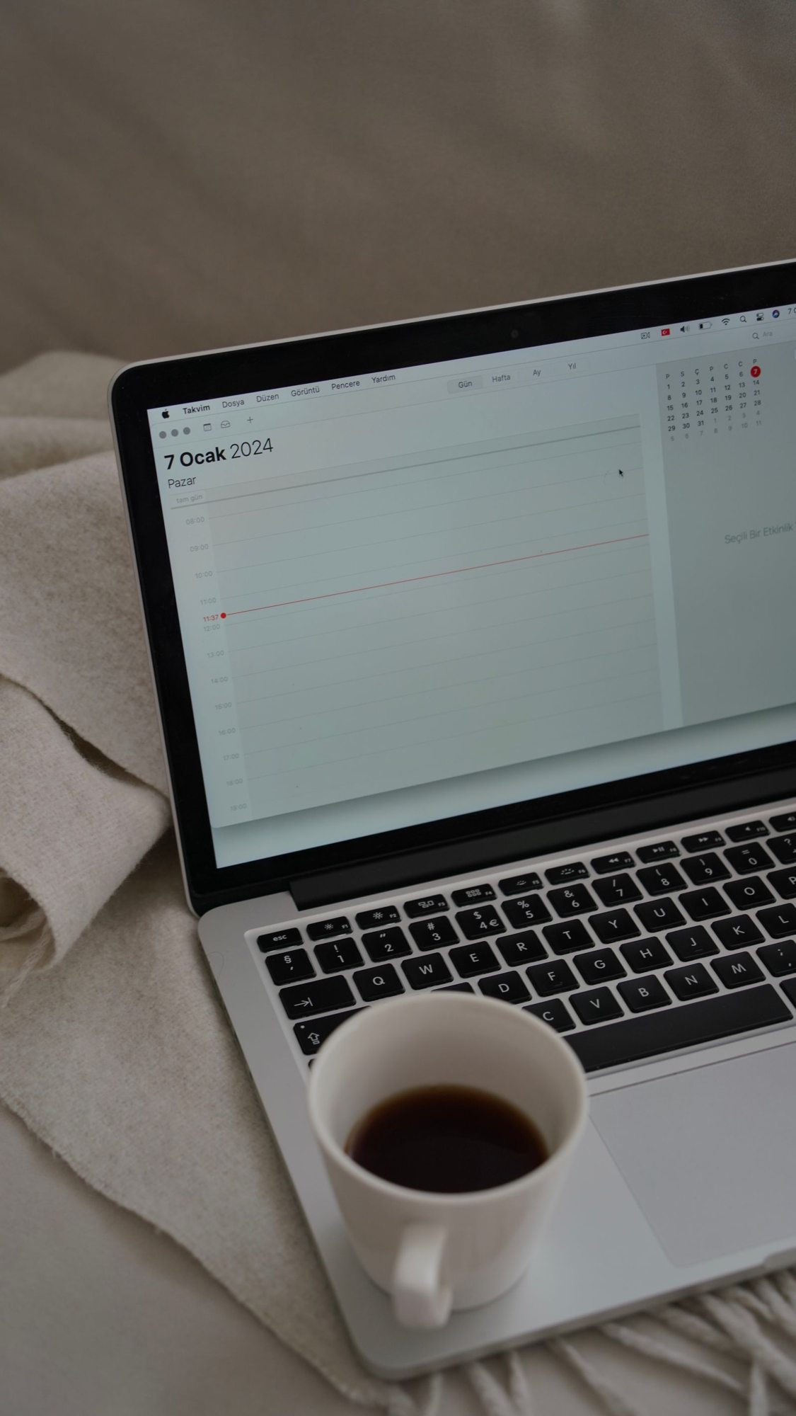 Digitaler Kalender auf einem Laptop neben einer Tasse