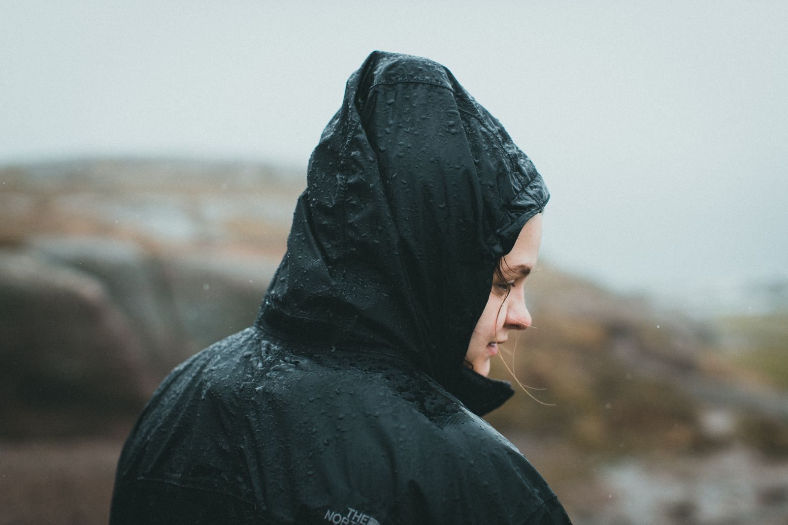 Person in einer wasserdichten Jacke im Regen