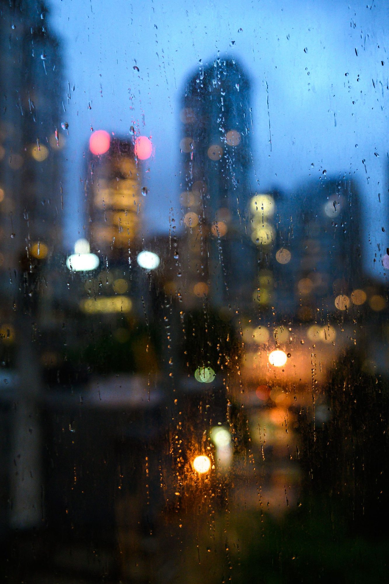 Regentropfen am Fenster vor einer städtischen Abendkulisse